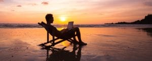 Business man with laptop working on the beach